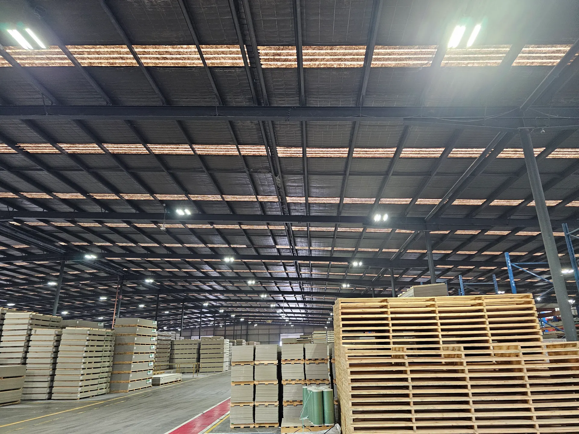 Warehouse roof with browned, perished fibreglass sheeting letting through little daylight, before replacement